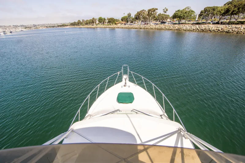 Slide: The Image of Bow view of 1997 Cabo 35 Express yacht cruising in calm waters near shoreline. - 13