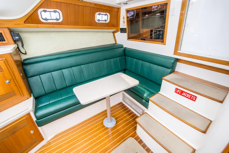 Slide: The Image of 1997 Cabo 35 Express cabin interior with green seating, table, and life jackets. - 20