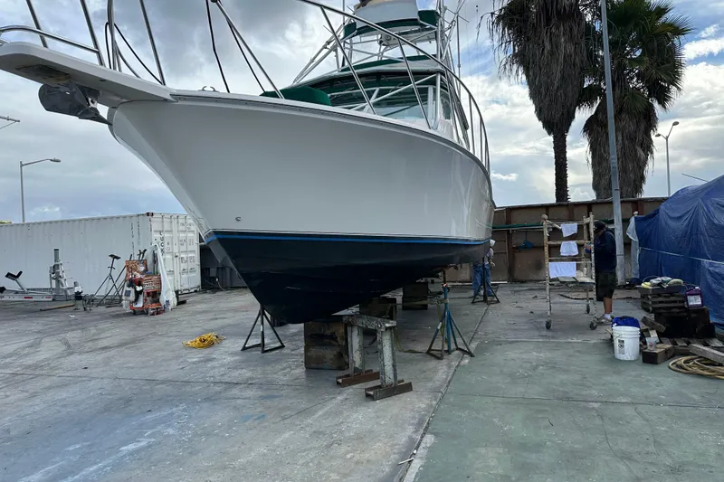 Slide: The Image of 1997 Cabo 35 Express boat on dry dock for maintenance, surrounded by equipment and palm trees. - 27