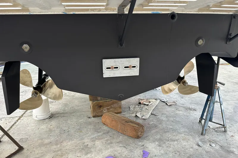 Slide: The Image of 1997 Cabo 35 Express boat underside with dual propellers and rudders in a maintenance area. - 29