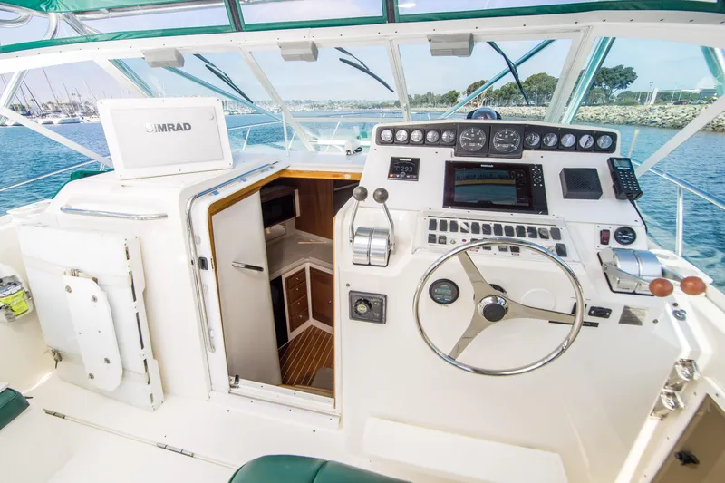 Slide: The Image of 1997 Cabo 35 Express boat cockpit with steering wheel, control panel, and cabin entrance. - 5