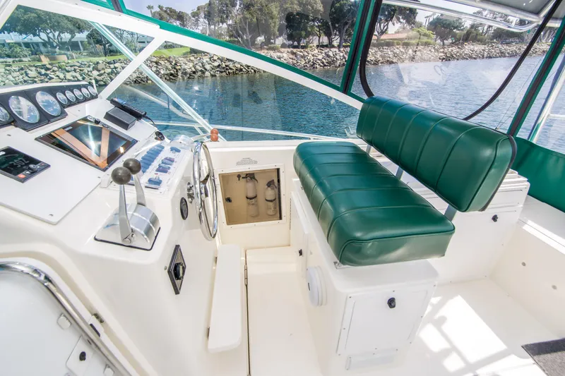 Slide: The Image of 1997 Cabo 35 Express boat cockpit with green seating and control panel, docked by the water. - 7