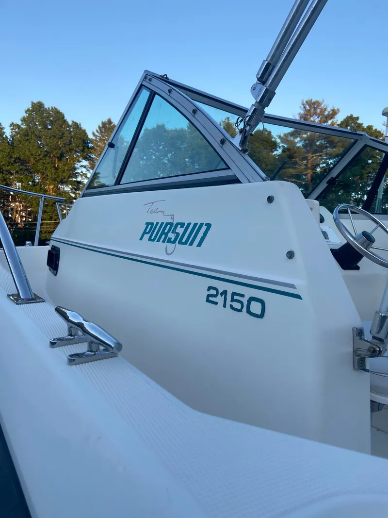 Slide: The Image of 1994 Pursuit 2150 boat side view with trees in the background. - 3