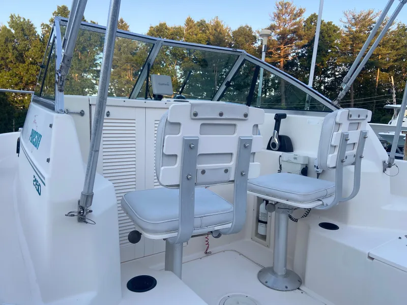 Slide: The Image of 1994 Pursuit 2150 boat cockpit with two white captain chairs and windshield. - 6
