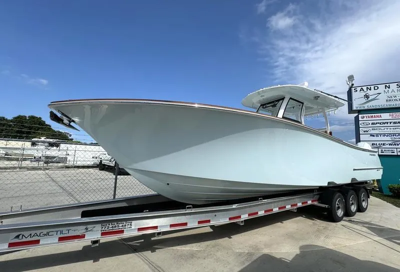 Slide: The Image of 2023 Phenom 34 boat on trailer at marina, clear sky background. - 1