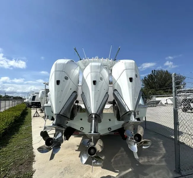 Slide: The Image of Triple outboard motors on a 2023 Phenom 34 boat under a clear blue sky. - 10
