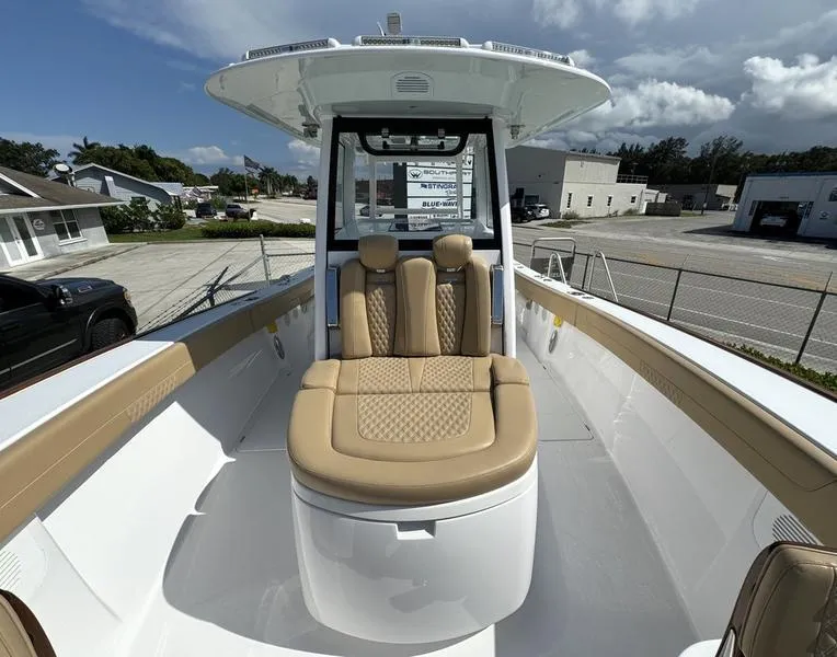 Slide: The Image of 2023 Phenom 34 boat with tan seating and sleek design in a marina setting. - 17