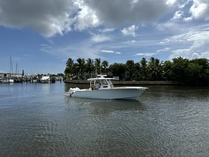 Slide: The Image of 2023 Phenom 34 boat cruising on a calm, scenic waterway with palm trees. - 2
