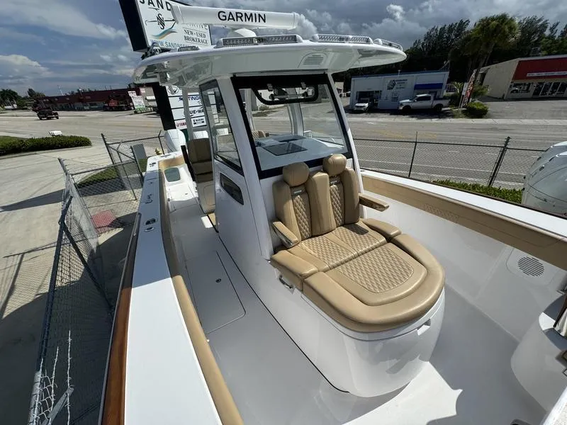 Slide: The Image of 2023 Phenom 34 boat with tan seating and Garmin electronics, docked outdoors. - 23