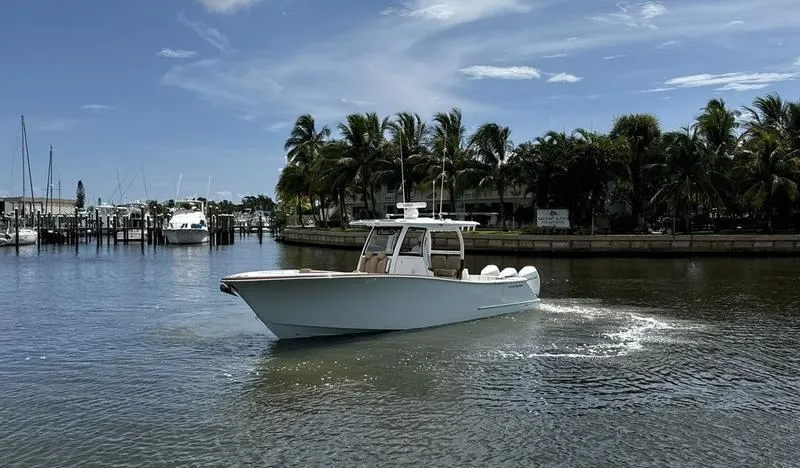 Slide: The Image of 2023 Phenom 34 boat cruising on a sunny day near palm trees and marina. - 3