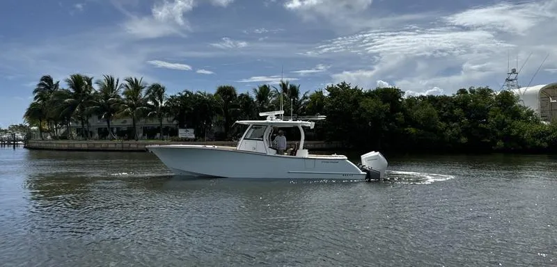 Slide: The Image of 2023 Phenom 34 boat cruising on a calm river with palm trees in the background. - 5