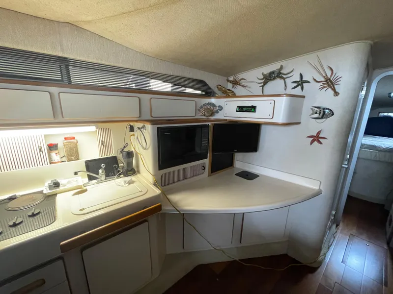 Slide: The Image of 1993 Sea Ray 400 Express Cruiser kitchen with stove, sink, microwave, and wall decor. - 21