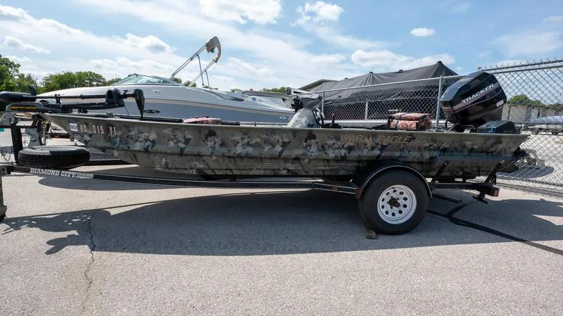 The Image of 2003 War Eagle 754 LDSV boat on trailer, camo design, parked outdoors. - 1