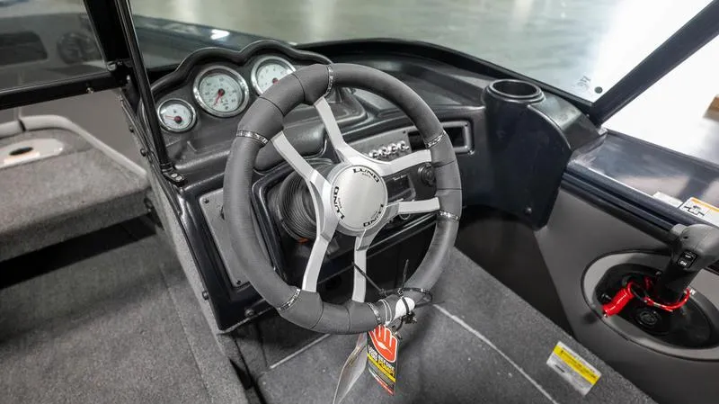 Slide: The Image of 2024 Lund 1875 Crossover XS boat interior with steering wheel and dashboard controls. - 14