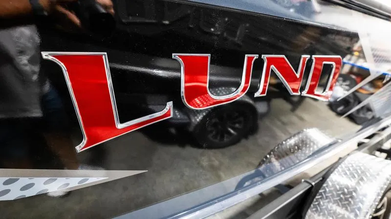 Slide: The Image of 2024 Lund 1875 Crossover XS boat logo in bold red lettering on a sleek black surface. - 5