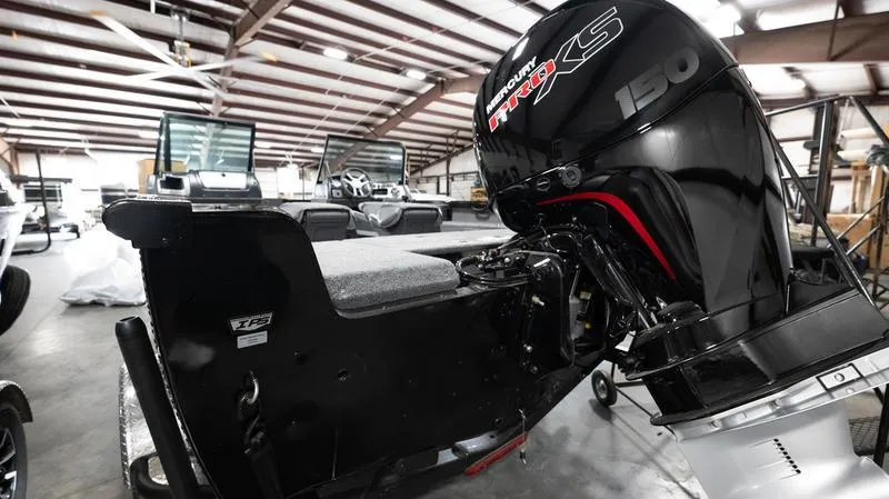 Slide: The Image of 2024 Lund 1875 Crossover XS boat with powerful Mercury 150 engine in a warehouse. - 7