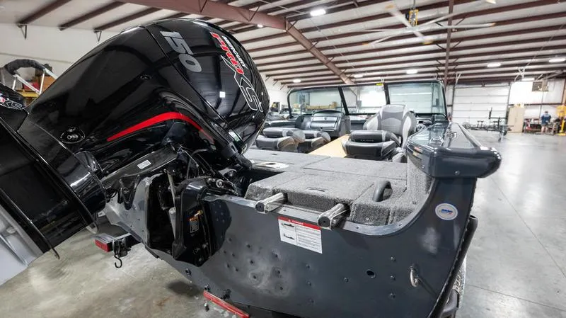 Slide: The Image of 2024 Lund 1875 Crossover XS boat with powerful outboard motor in a spacious warehouse. - 8