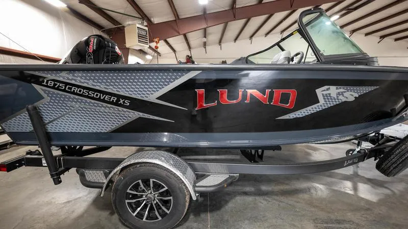 Slide: The Image of 2024 Lund 1875 Crossover XS boat in a showroom, showcasing sleek design and branding. - 9