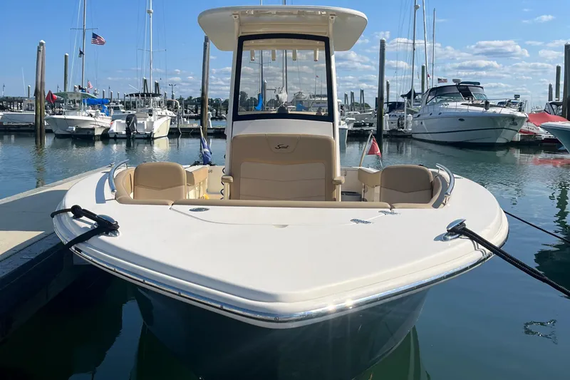 Slide: The Image of 2019 Scout 235 XSF boat docked at a marina with other boats in the background. - 2