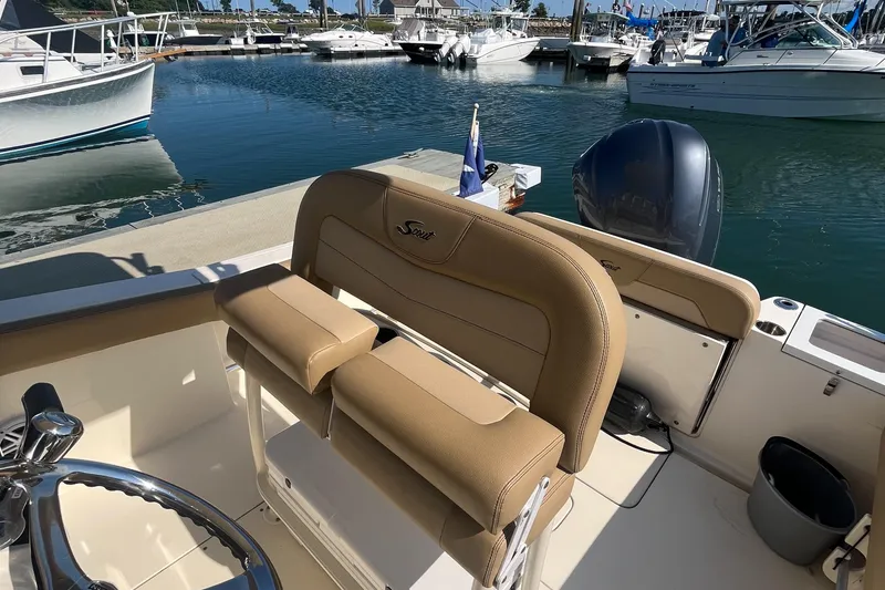 Slide: The Image of 2019 Scout 235 XSF boat interior with tan seating at marina. - 7