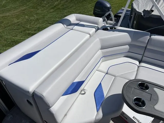 Slide: The Image of 2024 SunCatcher Select 18C boat interior with white and blue seating, cup holders, and Yamaha motor. - 10