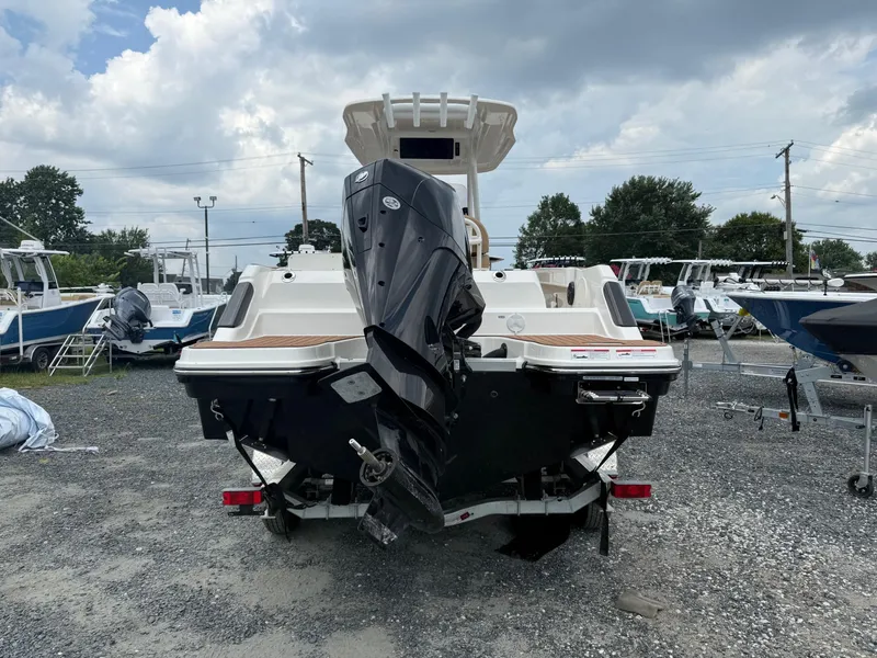 Slide: The Image of 2024 Bayliner Trophy T24CC boat with outboard motor, parked on gravel lot. - 21