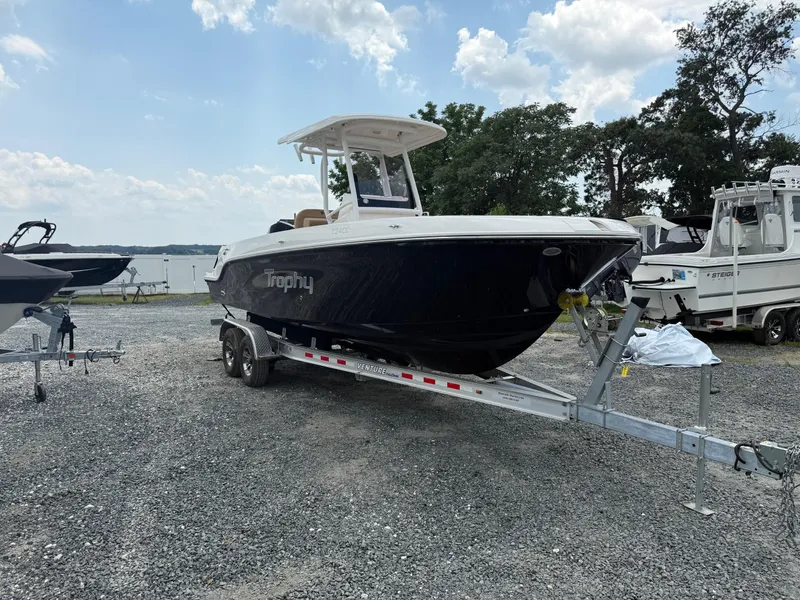 Slide: The Image of 2024 Bayliner Trophy T24CC boat on trailer, parked outdoors under a cloudy sky. - 23