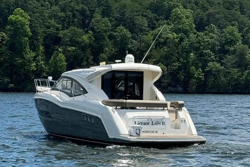 Slide: The Image of 2015 Carver C37 Coupe yacht cruising on a lake with forested shoreline. - 2