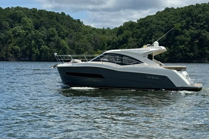 Slide: The Image of 2015 Carver C37 Coupe yacht cruising on a lake with forested hills in the background. - 3
