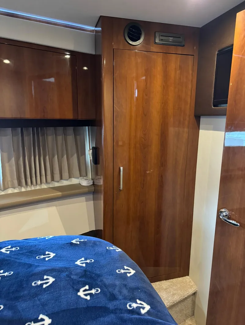 Slide: The Image of Interior of a 2015 Carver C37 Coupe with wooden cabinetry and nautical-themed bedding. - 34