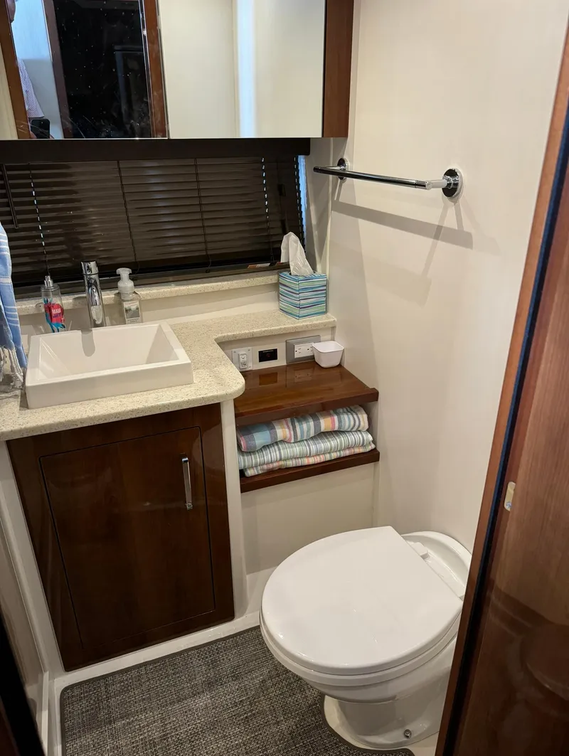 Slide: The Image of 2015 Carver C37 Coupe bathroom with sink, toilet, and storage shelves. - 37