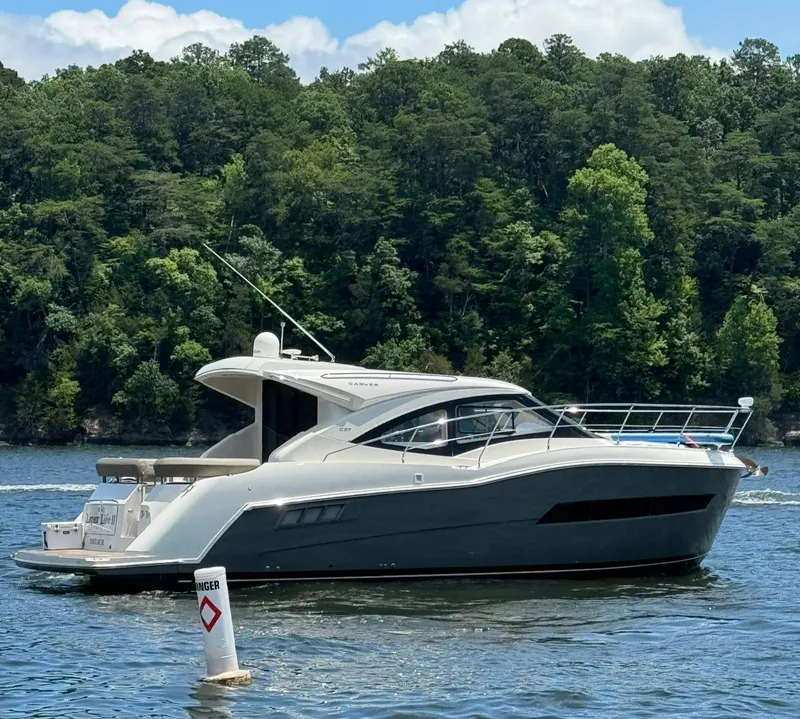 Slide: The Image of 2015 Carver C37 Coupe yacht cruising on a lake with forested shoreline. - 4