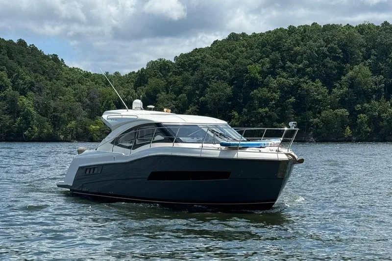 Slide: The Image of 2015 Carver C37 Coupe yacht cruising on a lake with forested hills in the background. - 5