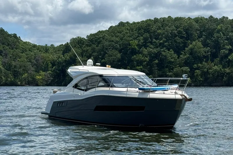 Slide: The Image of 2015 Carver C37 Coupe yacht on a serene lake with forested background. - 6