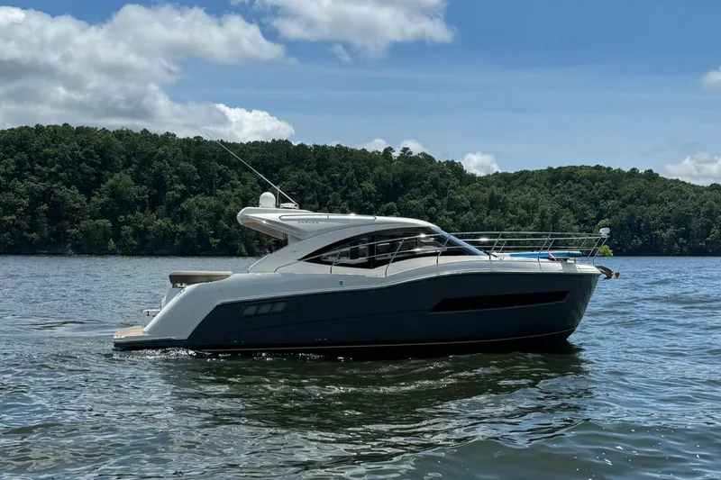 Slide: The Image of 2015 Carver C37 Coupe yacht on a serene lake with forested background. - 7