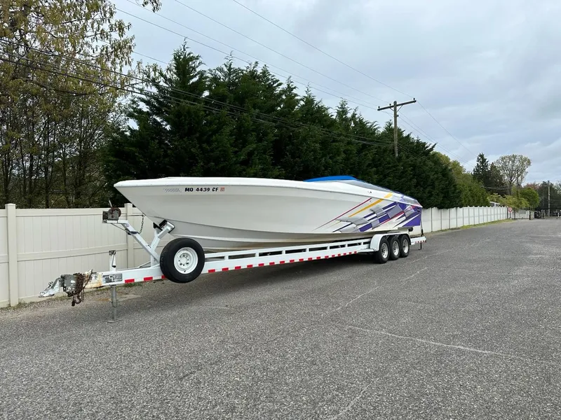 The Image of 1997 Outerlimits 37 Stiletto powerboat on a trailer, white with colorful graphics. - 0