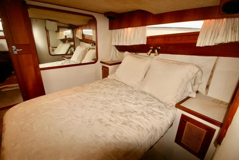 Slide: The Image of Luxurious cabin interior of 1986 Midnight Lace 44 Flybridge Express Cruiser with cozy bed and wood accents. - 19