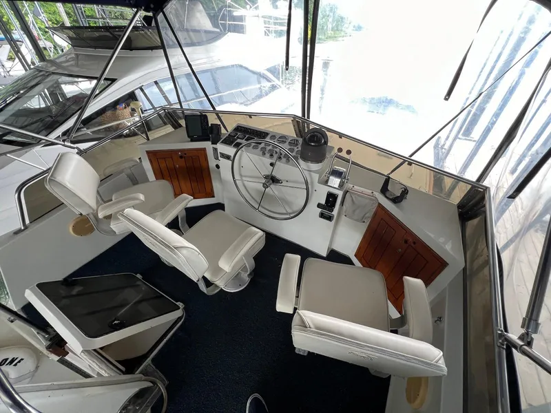 Slide: The Image of 1986 Midnight Lace 44 Flybridge Express Cruiser cockpit with white seating and control panel. - 7