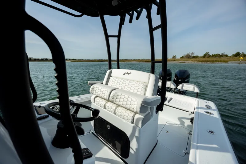 Slide: The Image of 2025 Yellowfin 26 Hybrid boat interior with steering wheel and seating on calm water. - 17