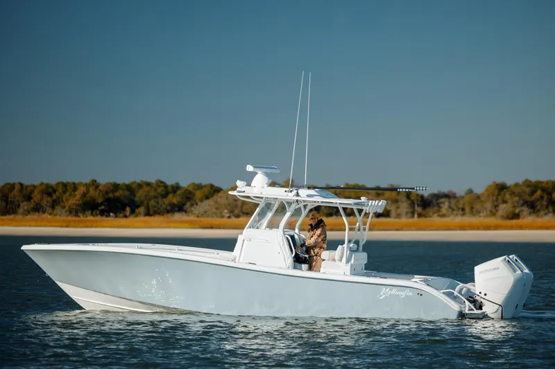 The Image of 2025 Yellowfin 32 boat cruising on calm water near a wooded shoreline. - 0