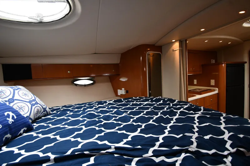 Slide: The Image of 1998 Cruisers Yachts 3870 Express cabin with bed, porthole, and kitchenette. - 33