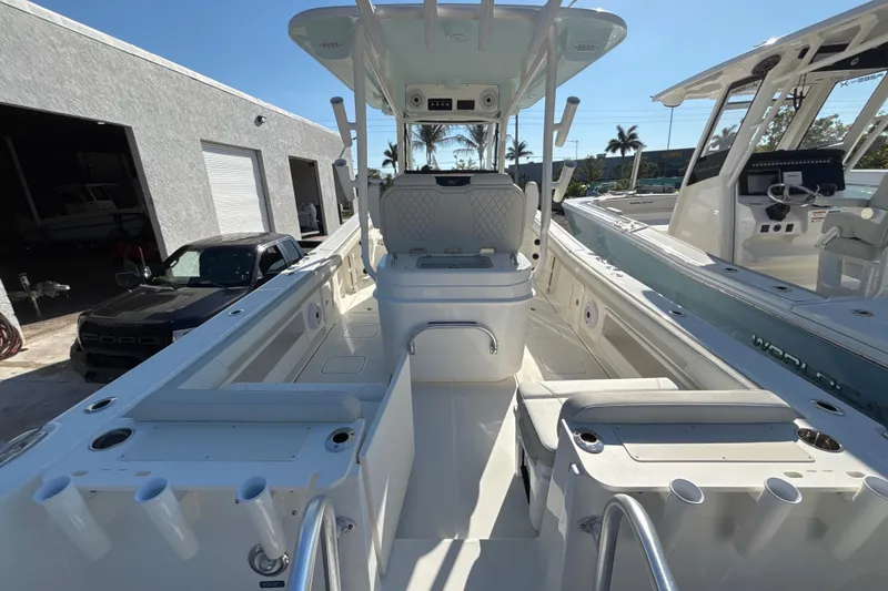 Slide: The Image of 2026 World Cat 295 CC boat interior with seating and rod holders, parked near a garage. - 3