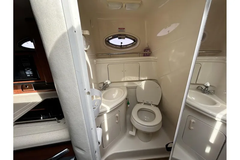 Slide: The Image of 2005 Sea Ray 280 Sundancer bathroom with sink, toilet, and porthole window. - 16