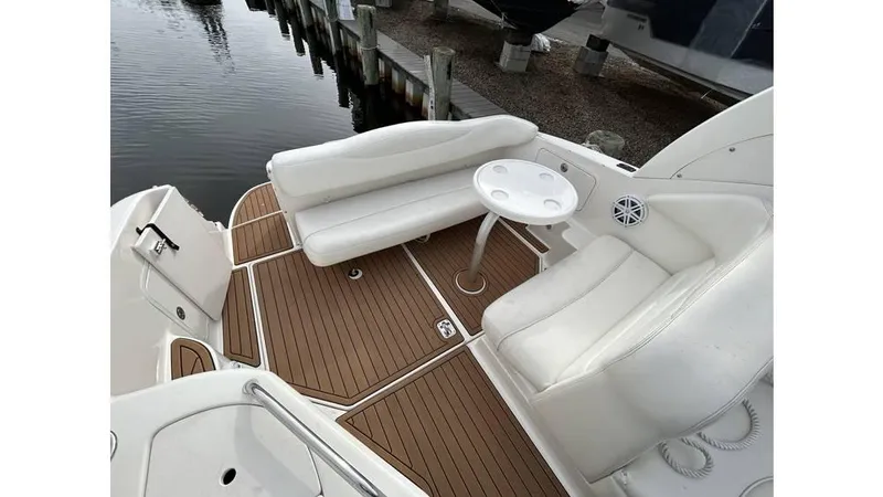 Slide: The Image of 2005 Sea Ray 280 Sundancer boat interior with white seating and wooden deck. - 6
