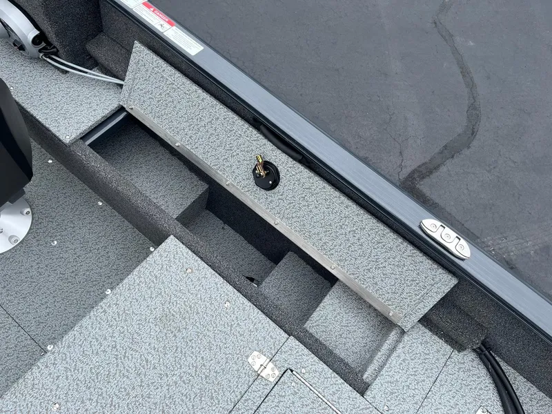 Slide: The Image of 2025 Lund 1650 Rebel XL SS boat interior, featuring storage compartments and textured flooring. - 18