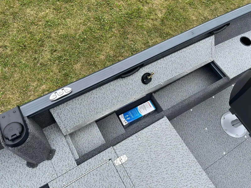 Slide: The Image of 2025 Lund 1650 Rebel XL SS boat interior with storage compartments and gray flooring. - 19