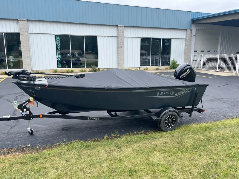 Slide: The Image of 2025 Lund 1650 Rebel XL SS boat on trailer, covered, parked outside a building. - 26