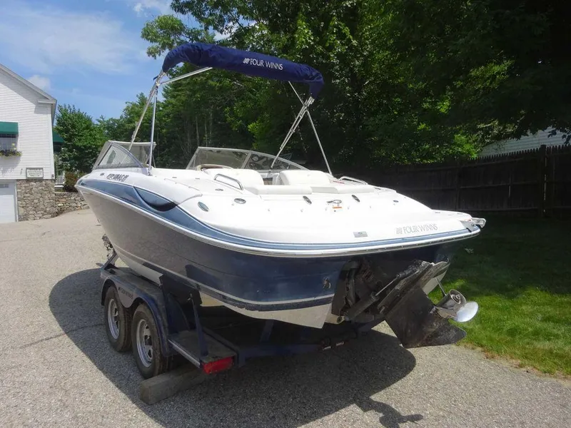 Slide: The Image of 2006 Four Winns H220 boat on trailer, parked outdoors with trees in the background. - 3