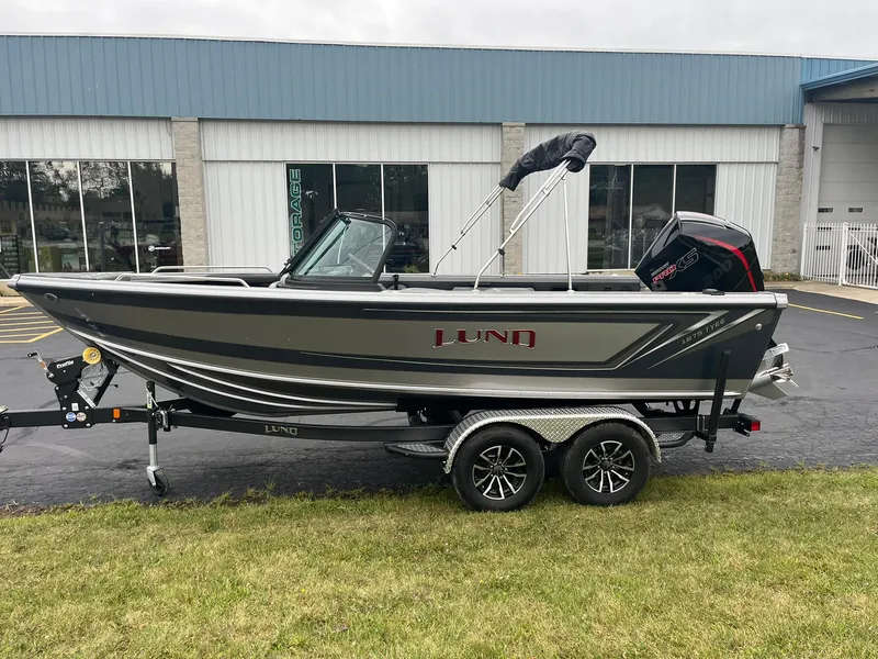 Slide: The Image of 2025 Lund 1875 Tyee boat on trailer, parked outside a building. - 0