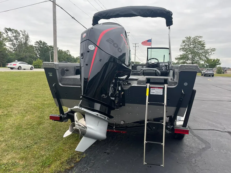 Slide: The Image of 2025 Lund 1875 Tyee boat with powerful outboard motor and ladder, parked on pavement. - 2